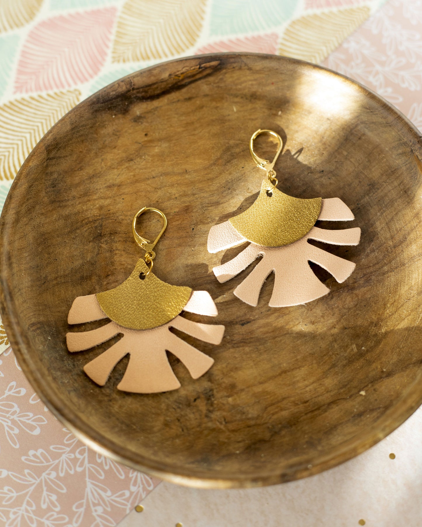 Boucles d'oreilles cuir bronze rose Chenoha Studio au design élégant et moderne posées sur un plateau en bois
