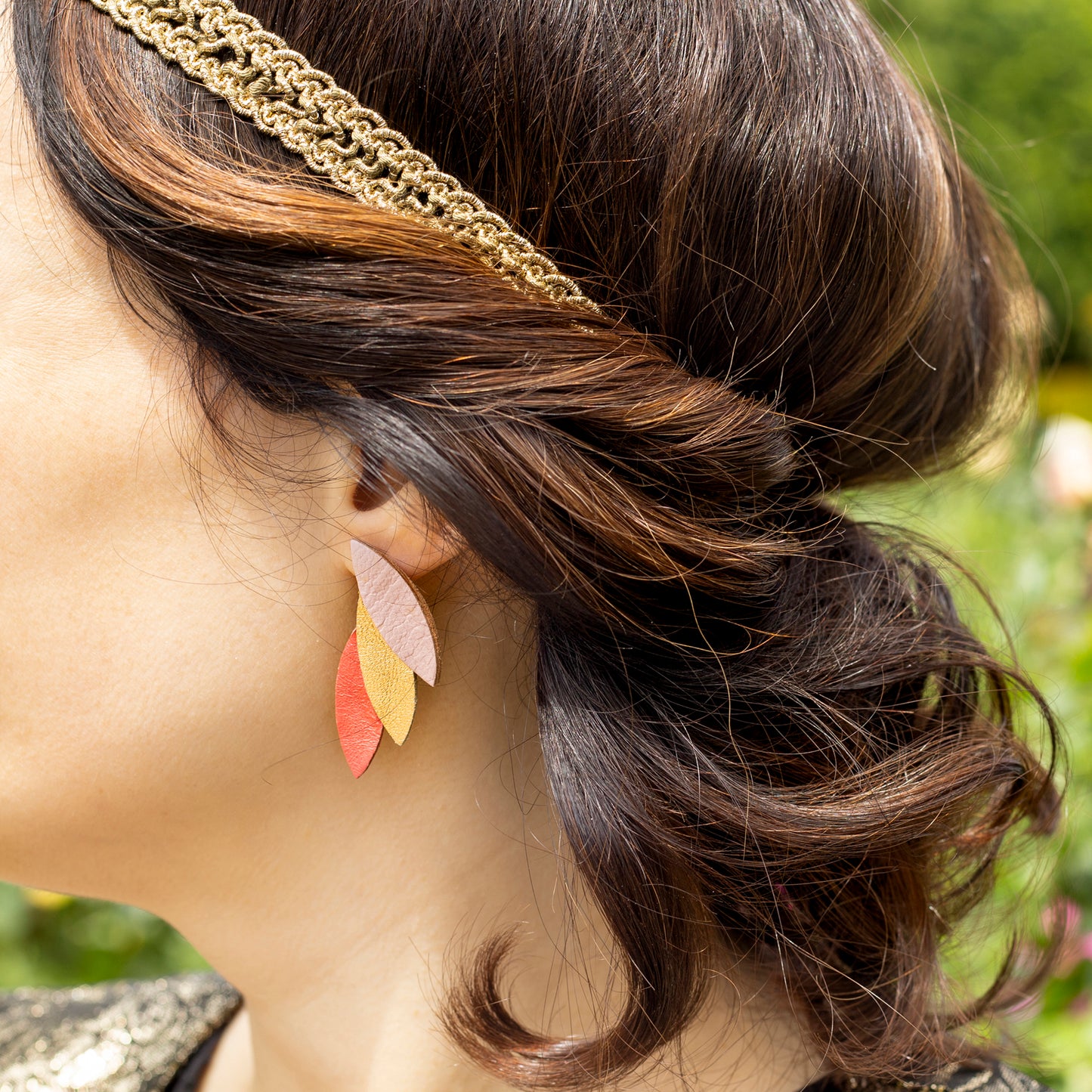 Boucles d'oreilles cuir vert bleu en feuilles multicolores portées par femme avec bandeau doré cheveux bruns