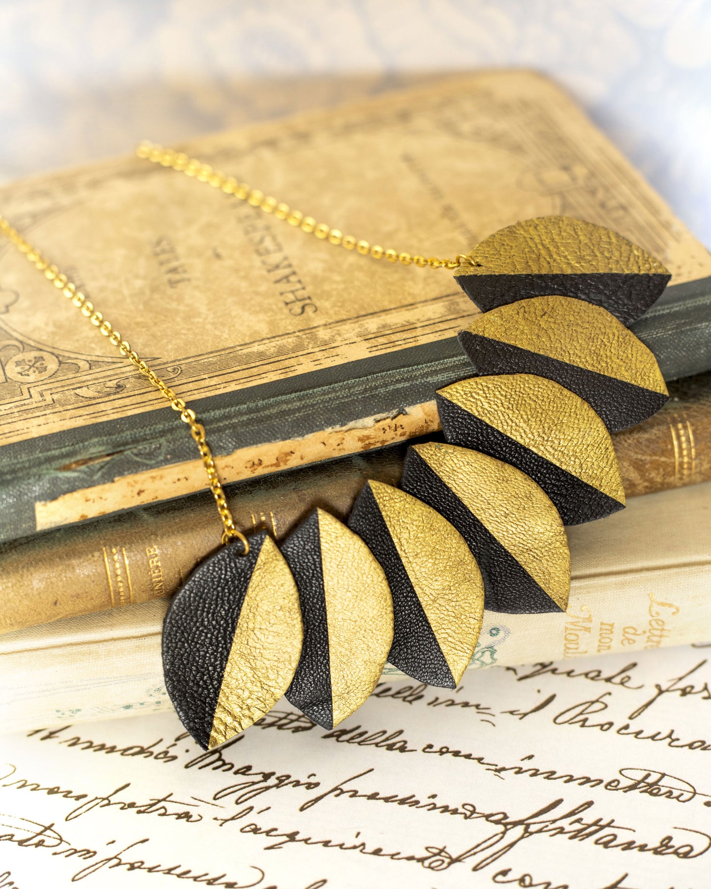 Collier plastron cuir recyclé Chenoha Studio en forme de feuilles dorées et noires sur chaîne dorée