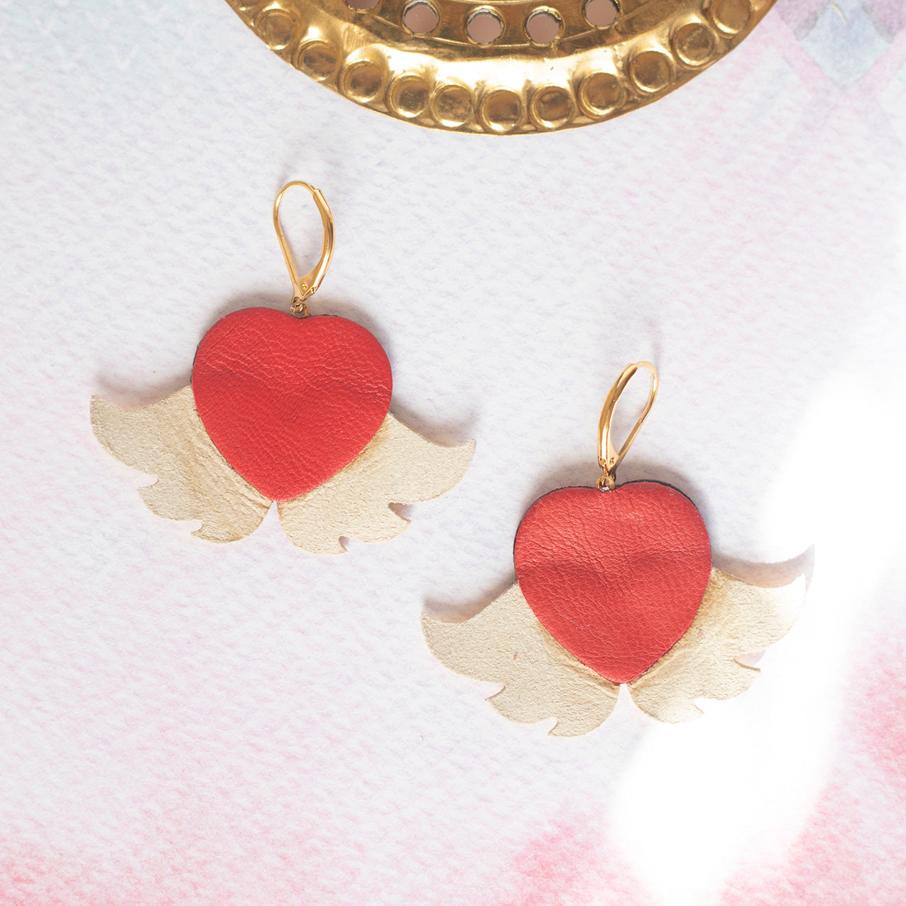 Ohrringe mit geflügelten Herzen aus Gold und metallisch rotem Leder