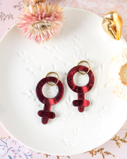 Metallisch rote Ohrringe mit femininem Symbol
