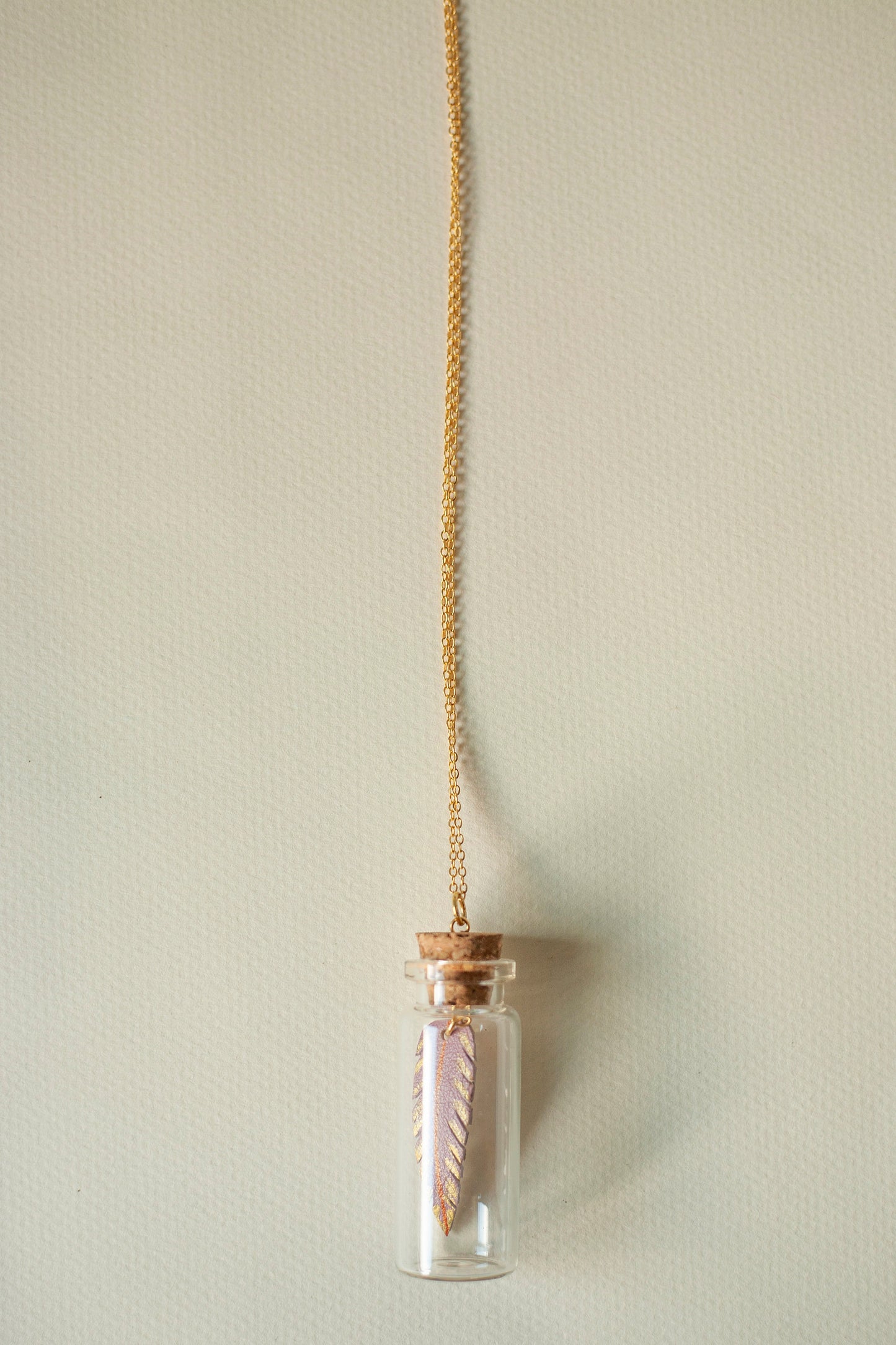 Long necklace with glass vial pendant and leather feather