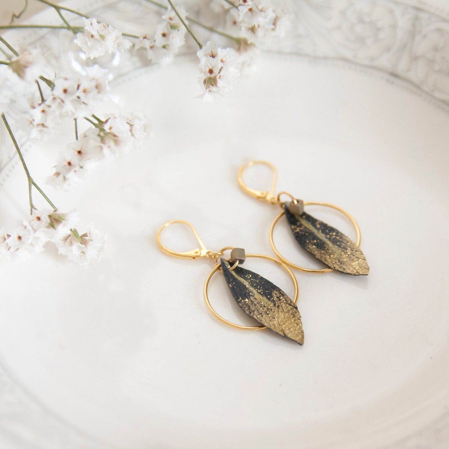 Feather hoop earrings in black and gold leather